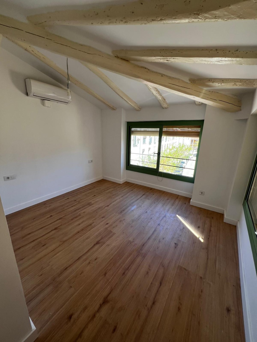 Reforma integral de vivienda con vigas de madera y suelo laminado