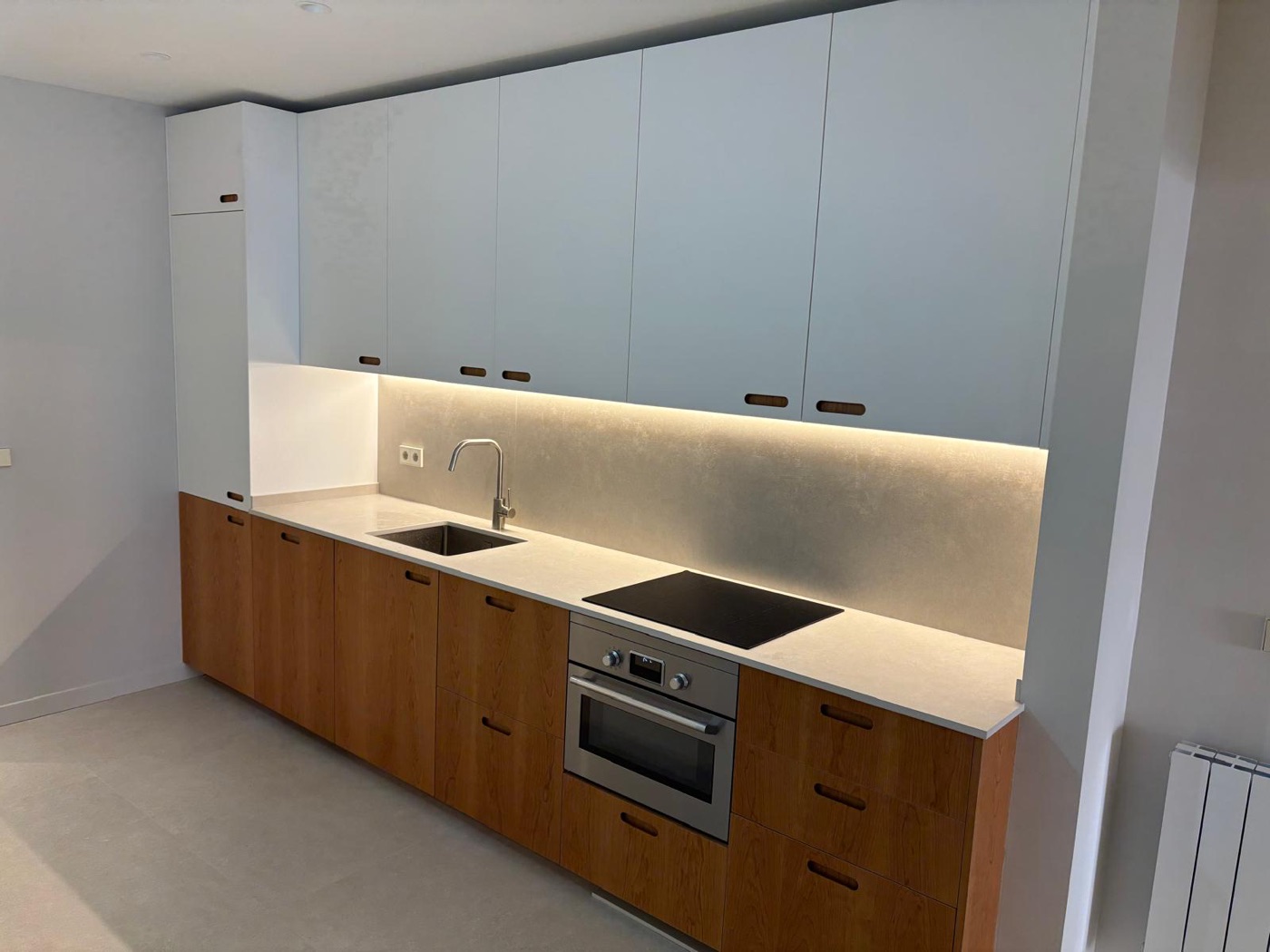 Reforma de cocina con muebles blancos y madera, encimera y placa de inducción